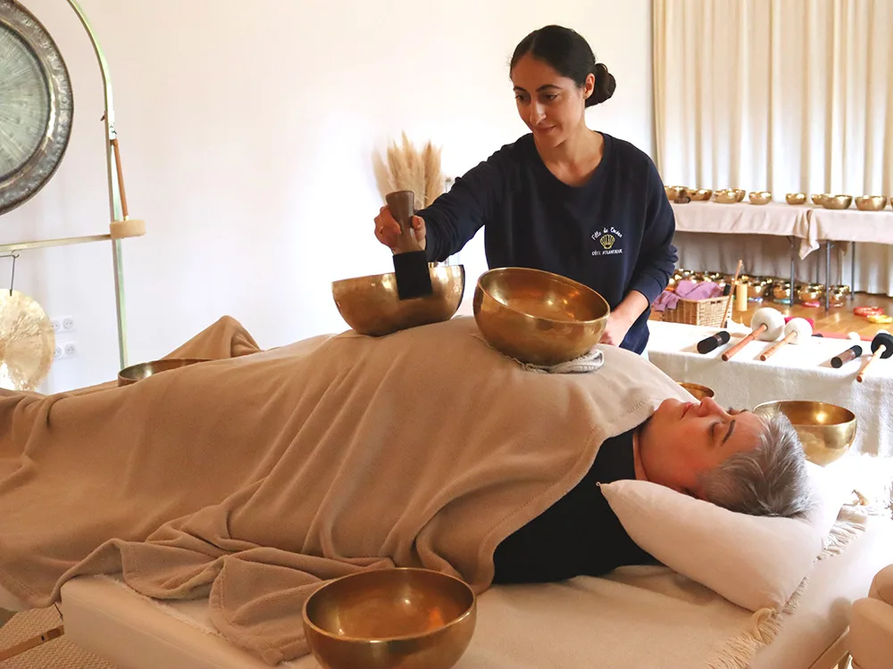 Séance de massage sonore avec bols népalais et gong, lors d'une formation de sonothérapie. Le massage sonore est une séance individuelle, profondément relaxante, sur table de massage ou futon.